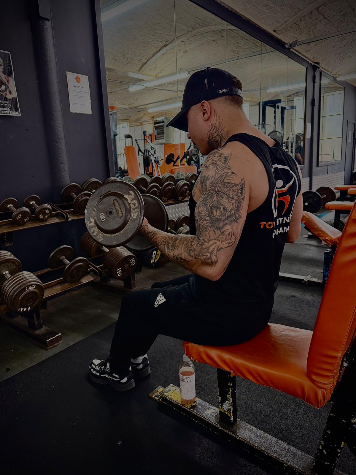Member doing seated dumbbell curls in Total Fitness vest