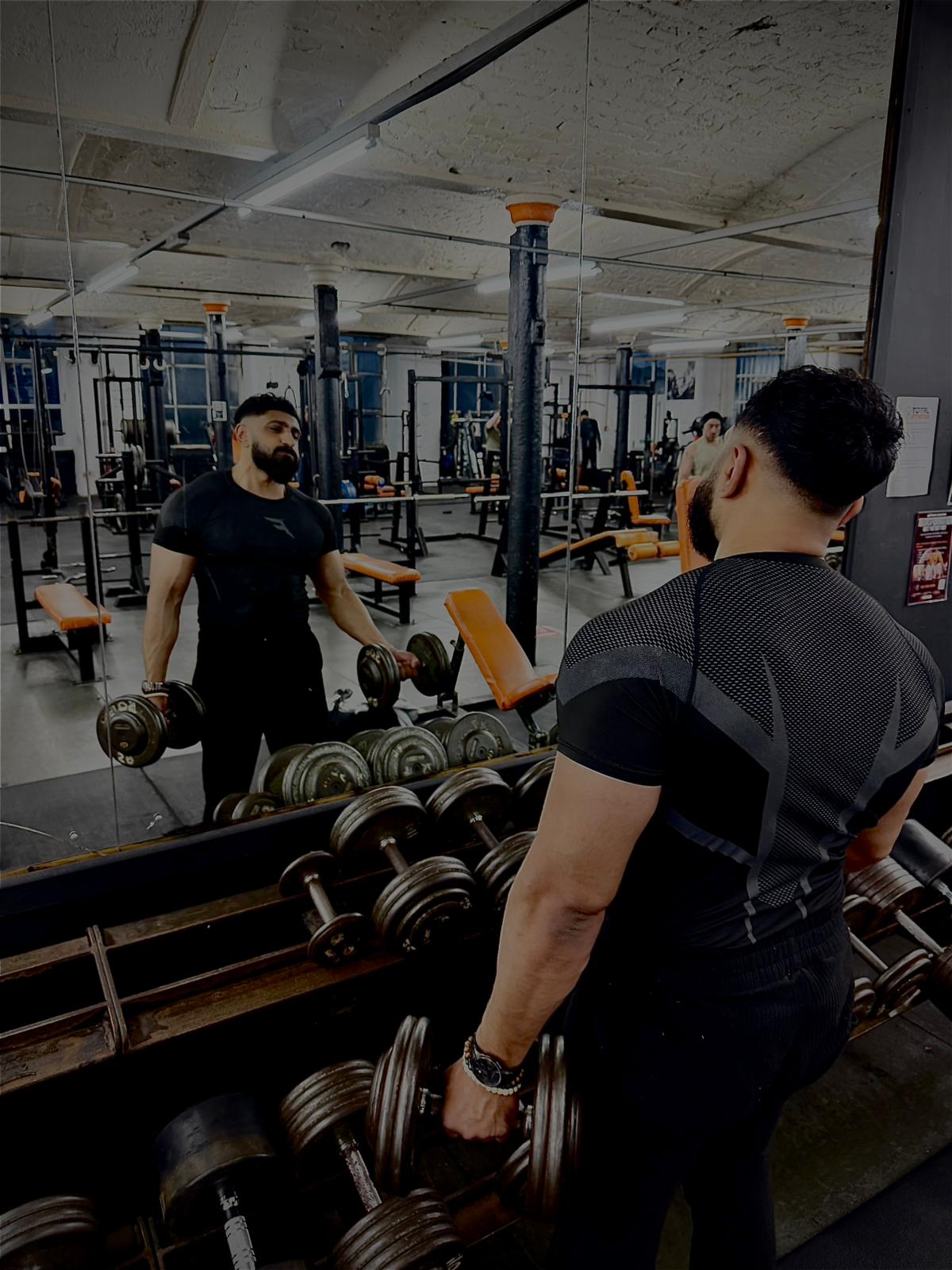 Member training with dumbbells in the mirror